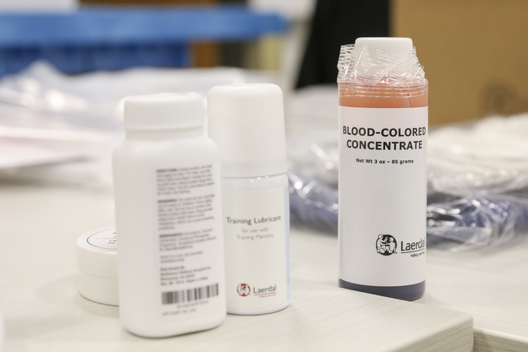 Three bottles and various packages sit on a table. One bottle is filled with red liquid and reads blood concentrate. 
