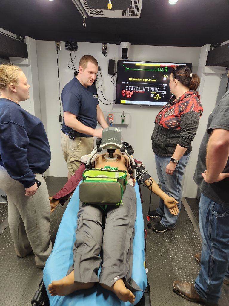 Four healthcare professionals around a table on a manikin on it