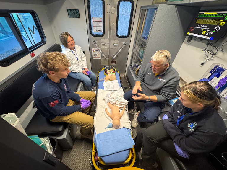 Simulation participants sitting around gurney during 2026 Johnson County EMS Saturday