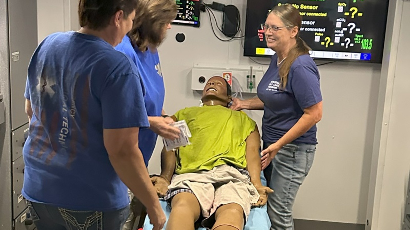 Three healthcare professionals around a table on a manikin on it