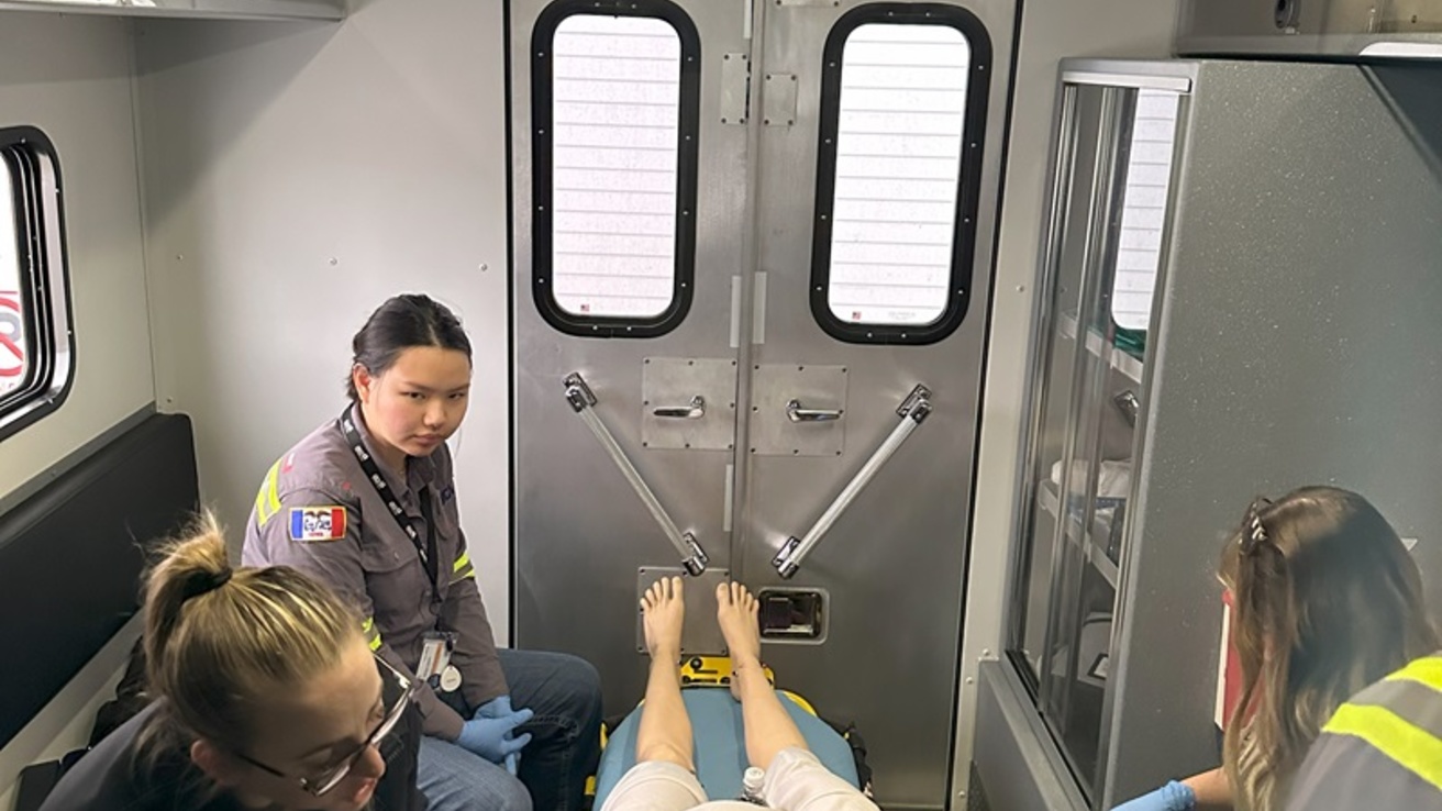 Three healthcare professionals around a table on a manikin on it