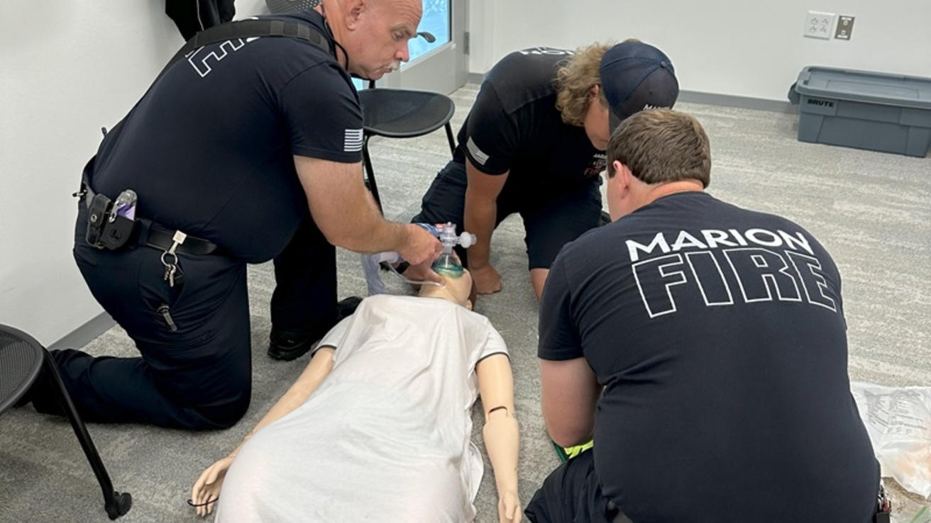 Three healthcare professionals around a manikin on the floor