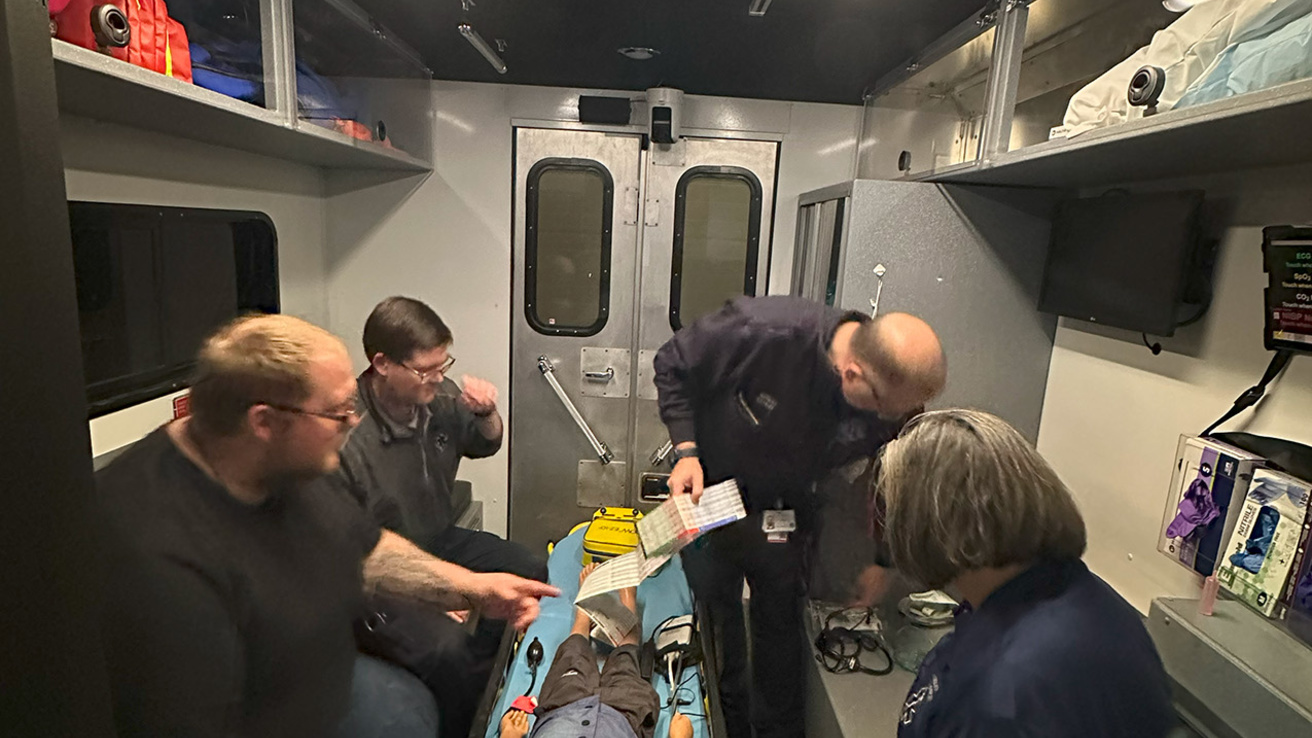 Four healthcare professionals around a table on a manikin on it