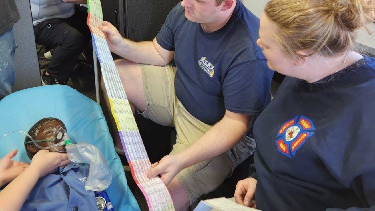 Three healthcare professionals around a table on a manikin on it